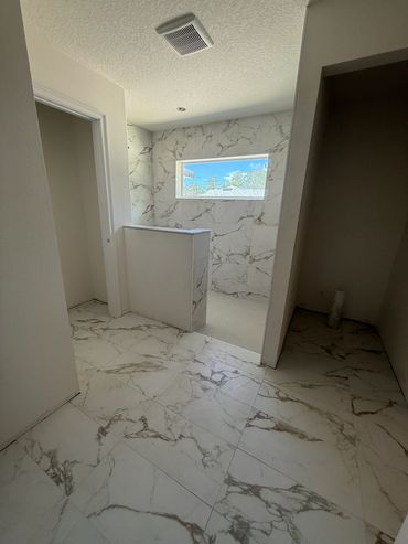 Modern bathroom with marble tiles and a window letting in natural light.
