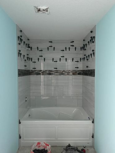 Bathtub with newly installed wall tiles and spacers in a bathroom under renovation.