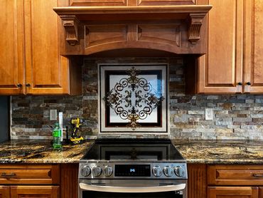 Modern kitchen stove with decorative tile backsplash and wooden cabinets.