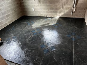 Newly installed dark patterned floor tiles in an unfinished room.