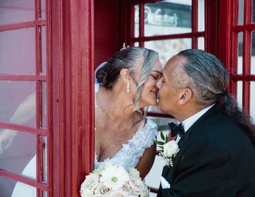 Bride and Groom kissing in the phone booth on the Queen Mary on their wedding day. Long Beach CA