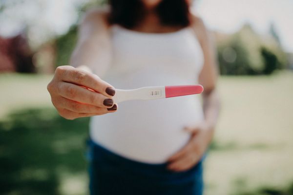 Positive pregnancy test results held in hand of pregnant woman