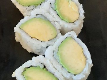 Avocado sushi rolls served on a black plate.