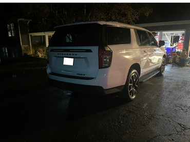White Chevrolet Suburban RST parked at night near a garage.