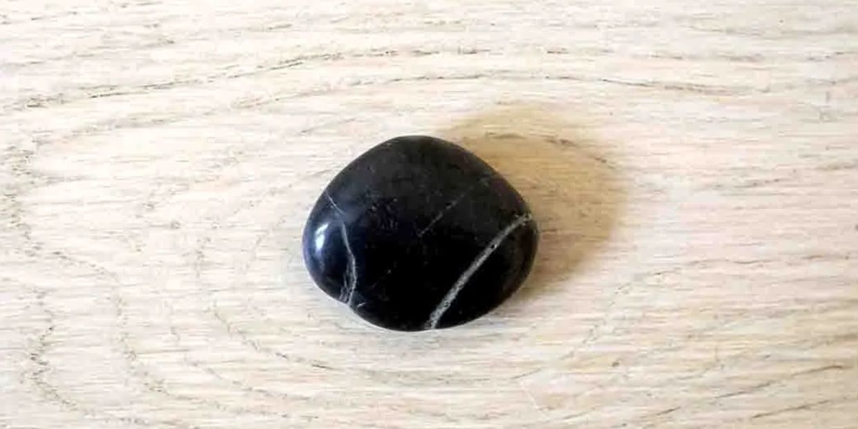 A variegated black pebble on a wooden table