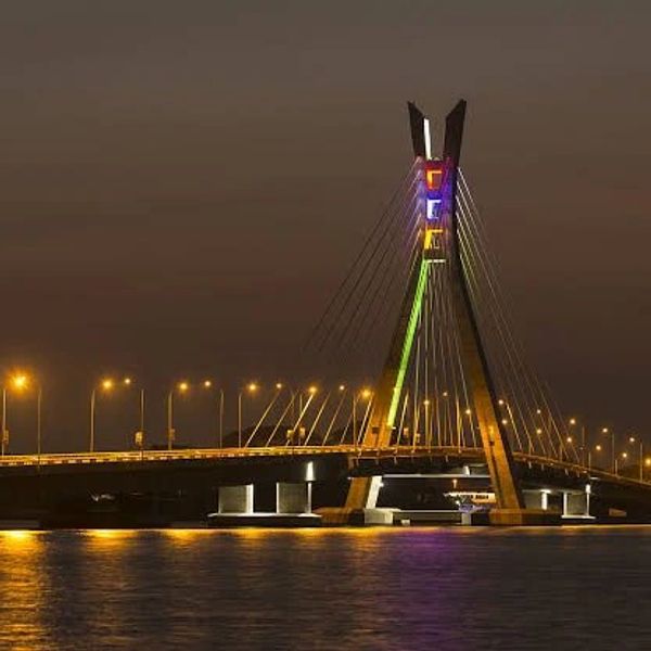 Illuminated cable-stayed bridge at night over water.