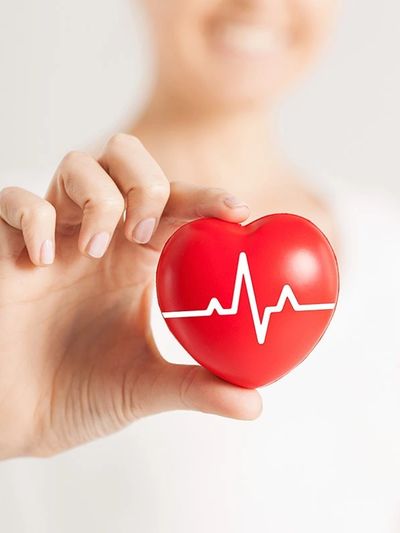 Hand holding a red heart with a white heartbeat line.