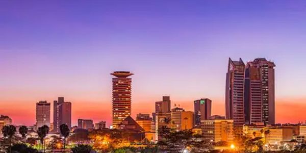 City skyline at dusk with colorful sunset and illuminated buildings.