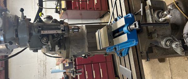 Industrial milling machine setup with blue vise in a workshop.