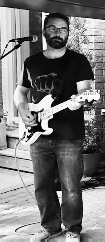 Man playing electric guitar and singing into a microphone.