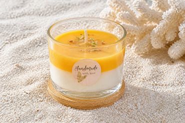 Handmade two-tone candle on a wooden coaster.