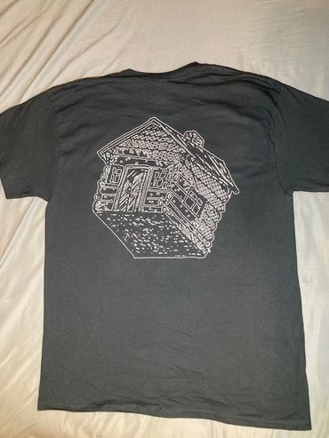 Black t-shirt with a white line drawing of a cabin on the back.