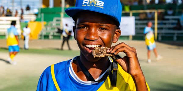 Young boy bites a gold medal proudly at a sports event.