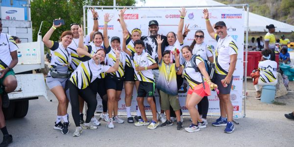 Group of cheerful runners posing with raised hands after a race event.