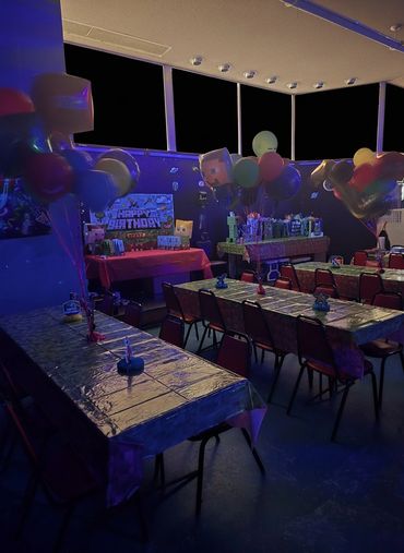 Dimly lit Minecraft-themed birthday party setup with balloons and decorated tables.