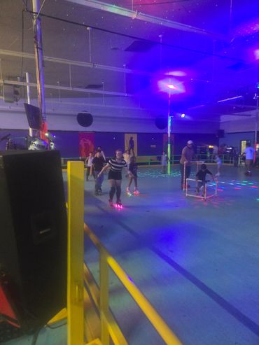 People roller skating under colorful lights in an indoor rink.