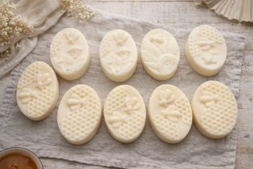 Oval soaps with bee and honeycomb designs arranged on a cloth.
