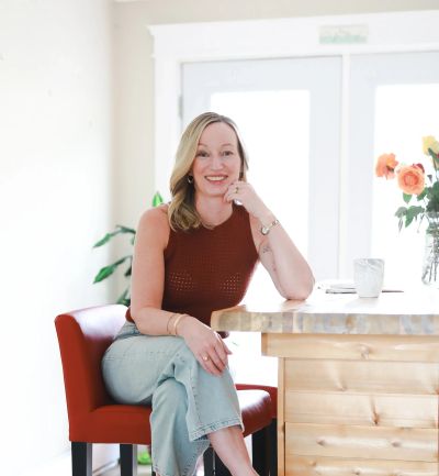 Woman sitting at a wooden table, smiling.