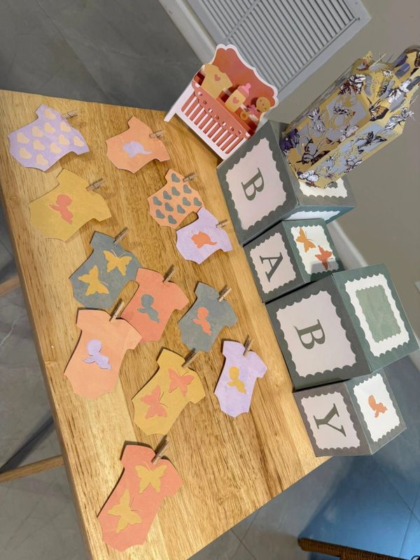 Decorative baby-themed paper cutouts and blocks on a wooden table.
