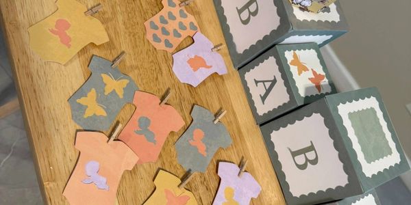 Decorative baby-themed paper cutouts and blocks on a wooden table.