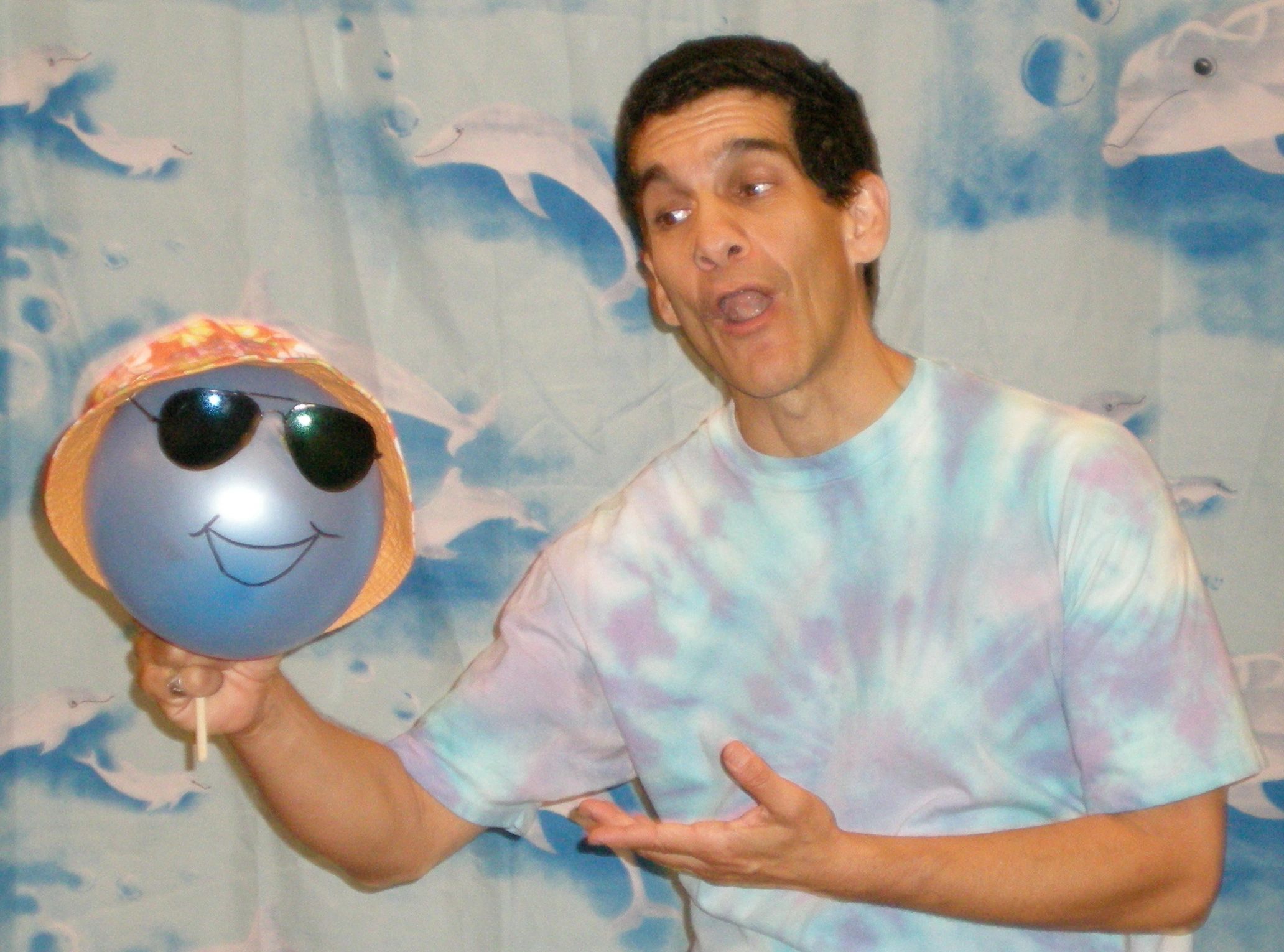 Barry in a blue-and-purple tie-dyed shirt, against a marine blue background printed with dolphins, h
