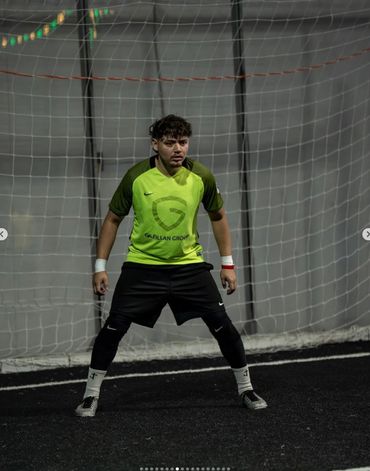 A focused soccer goalkeeper stands ready in front of the net during a match.