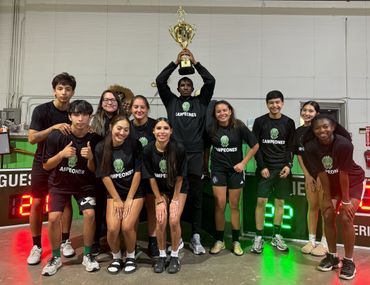 A victorious sports team poses with their championship trophy indoors.