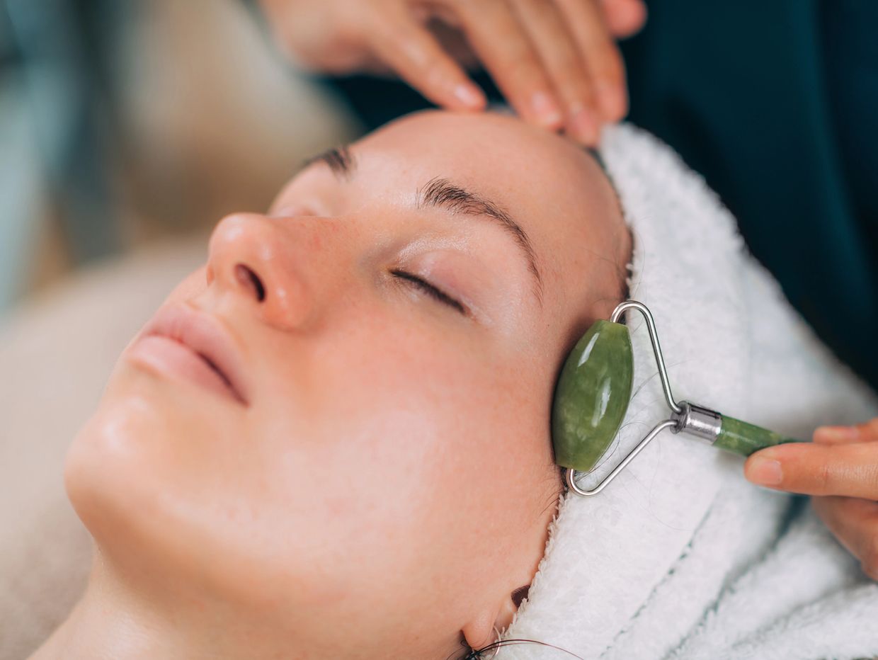 Person receiving a relaxing jade roller facial treatment.