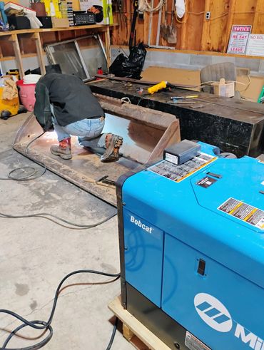 Person welding metal inside a workshop with equipment around.