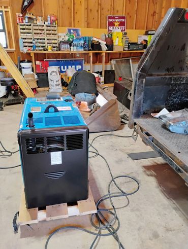 Person working in a cluttered workshop with machinery and tools.