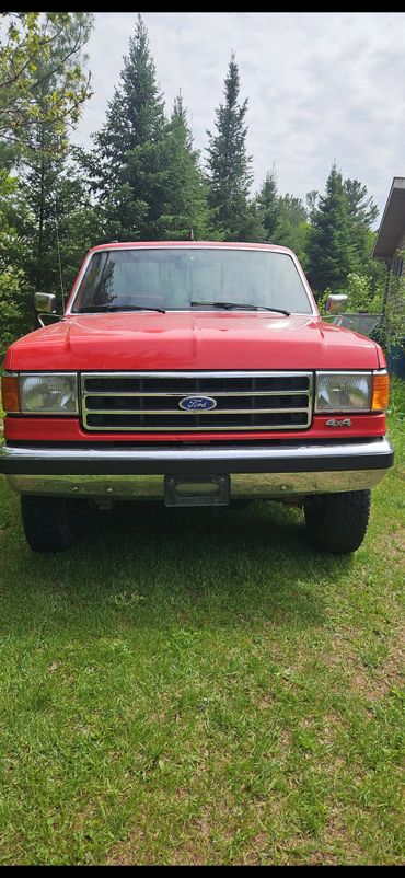 Front view of a red Ford 4x4 truck parked on grass.