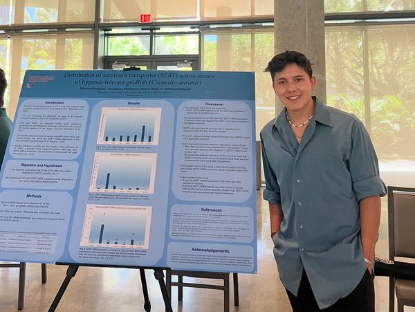 Student presenting research on serotonin transporter in goldfish at a science event.