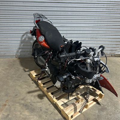 A dismantled motorcycle engine and parts on a wooden pallet.