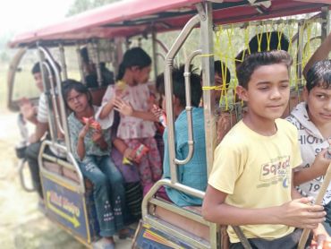 Children are enjoying a ride on a colourful open vehicle outdoors.