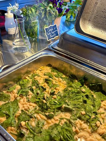 Braised white beans with greens in a buffet tray labeled vegan.