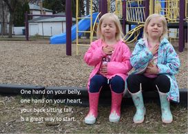 Photo of twin girls practicing mindful breathing. "One hand on your belly, one hand on your heart."