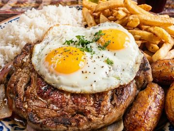 Plato con bistec, huevos fritos, arroz y papas fritas.
