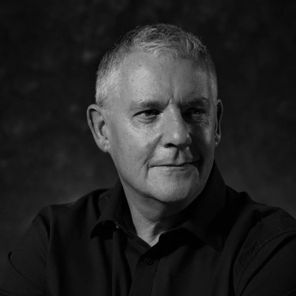 Black and white portrait of a thoughtful older man in a dark shirt.