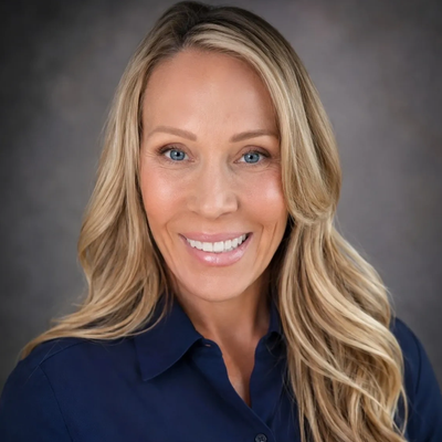 Smiling blonde woman with blue eyes wearing a navy shirt.