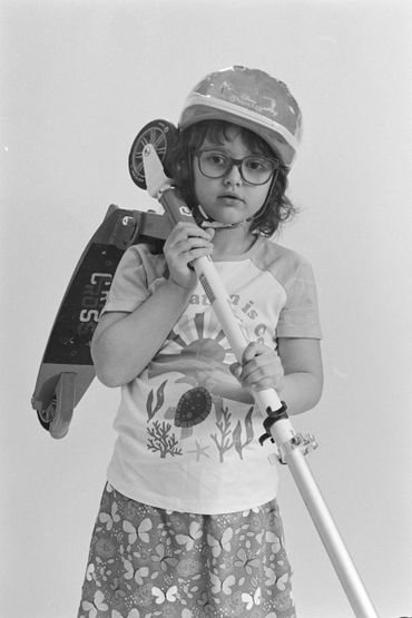 Young child wearing a helmet and glasses holding a scooter.