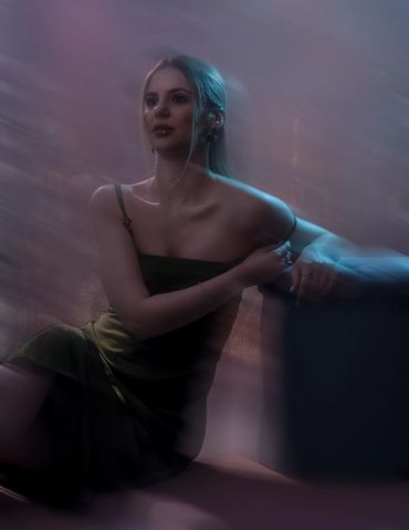 Young woman in a dark dress with soft, dreamy lighting and a blurred effect.