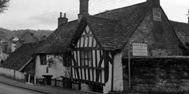 Historic timber-framed house with a steep roof in a quaint village.