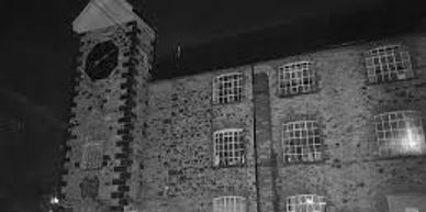 Old stone building with clock tower lit at night.