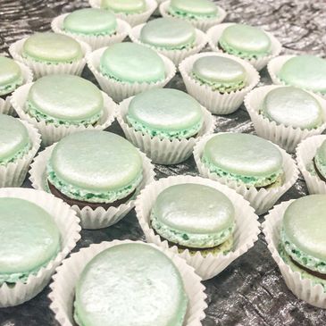Slightly shimmery mint green mIni french macarons chocolate filling sit closely next to each other i