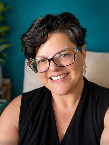 Smiling person with short dark hair and glasses.