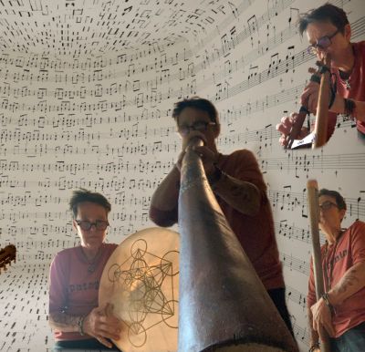 Person playing didgeridoo and drums surrounded by music notes.