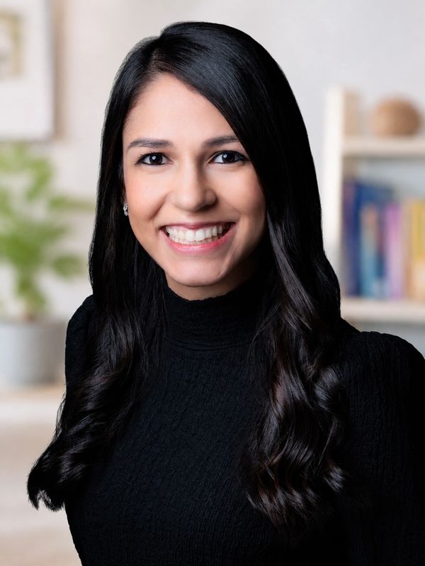 Smiling woman with long dark hair wearing a black top.