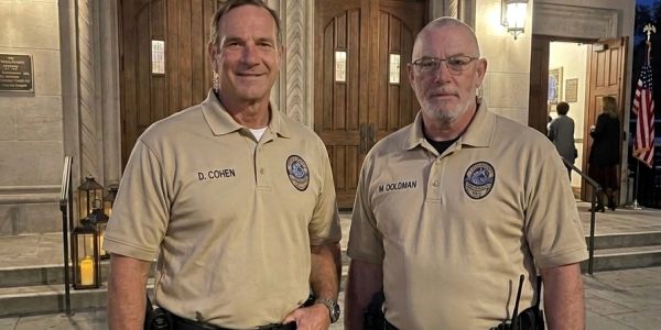 Two uniformed officers standing in front of a synagogue at night.
