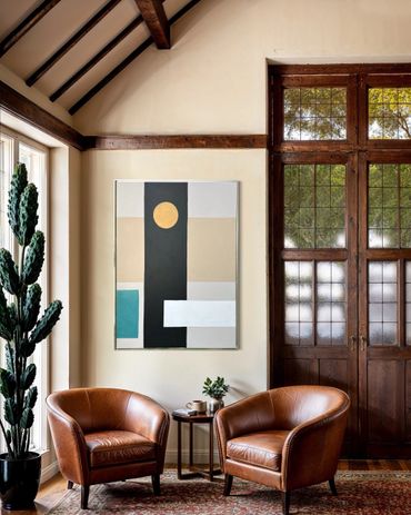 Cozy sitting area with leather chairs, abstract art, and tall cactus by a large window.