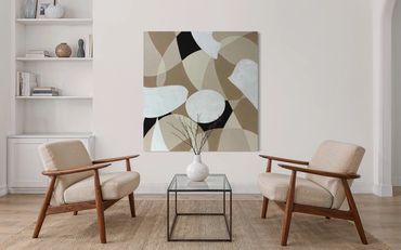 Minimalist living room with beige chairs, a glass coffee table, and abstract wall art.